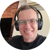 Yuriy Seniuk smiling, wearing glasses and headphones